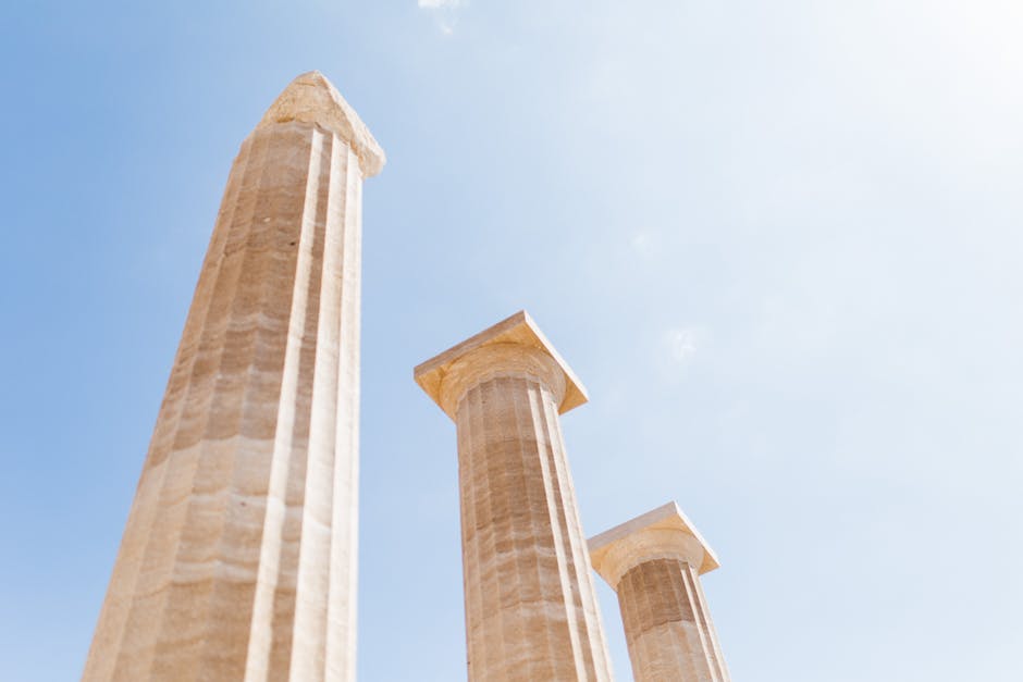 Low angle shot of ancient columns against a bright blue sky.