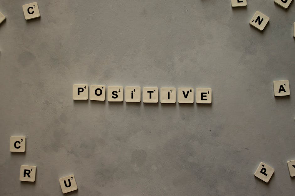 Scrabble tiles arranged to spell 'positive' on a gray textured surface, conveying optimism.