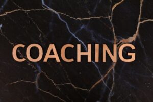 Wooden letters spelling 'Coaching' on dark marble surface, emphasizing guidance and mentorship.